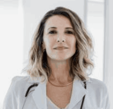 Person in a white coat with a stethoscope, standing indoors.