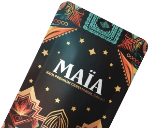 Black packaging of MAÏA ceremonial cacao with colorful geometric patterns.